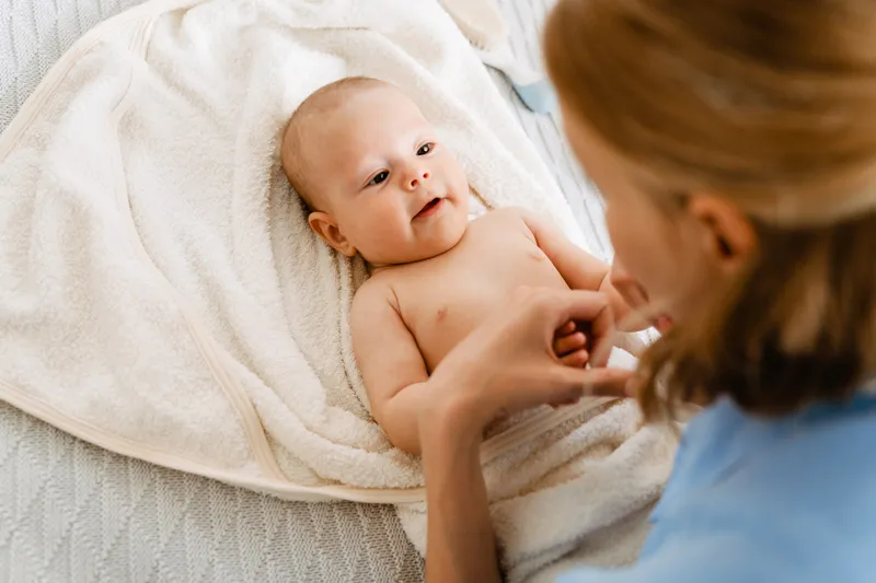 Bebé recostado sobre una toalla con su mamá (imagen de banco)